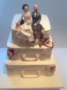 a wedding cake made to look like luggage with two people sitting on top of it