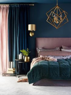 a bedroom with blue walls, gold accents and green bedding in the center is a chandelier