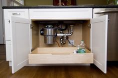 an open cabinet with a coffee maker and water bottle in the bottom drawer next to it