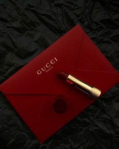 a red envelope with a gold pen on it and the word gucci next to it