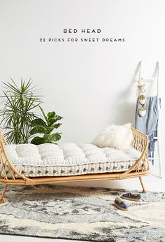 a bed that is sitting in the middle of a room next to a potted plant