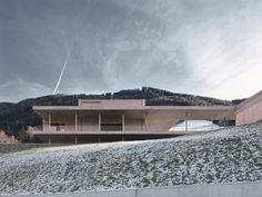 a building on top of a snowy hill with mountains in the backgroung