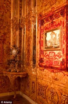 an ornately decorated room with gold and red wallpaper, paintings on the walls