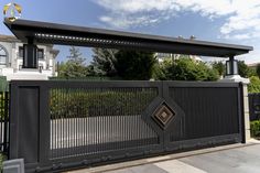 a black fence with an ornamental design on the top and bottom, in front of a house