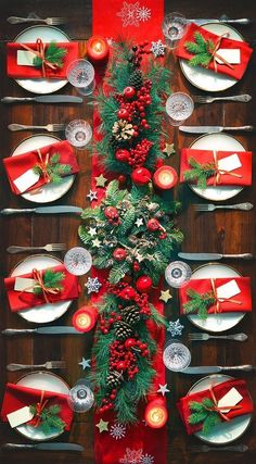 a christmas table setting with candles, plates and red napkins on the place settings