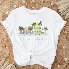 a white t - shirt with the words, the keys on it and palm trees