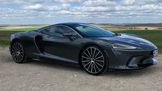 a grey sports car parked on top of a dirt field