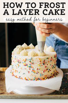 a person frosting a cake with icing and sprinkles