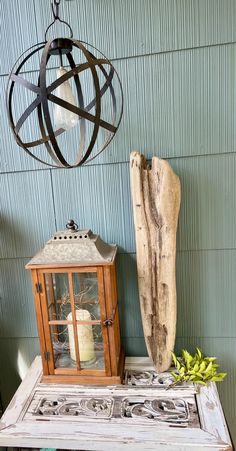 a wooden lantern sitting on top of a table next to a piece of driftwood