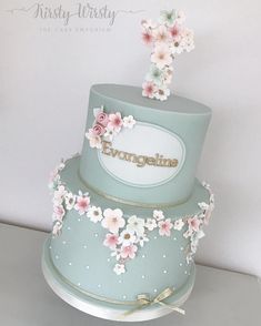 a three tiered cake with flowers on the top and bottom is decorated in pastel blue frosting