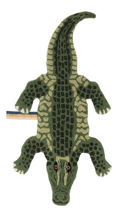 a stuffed alligator is laying on the ground with a pencil in it's mouth