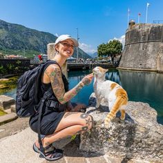 a woman petting a cat on the side of a river