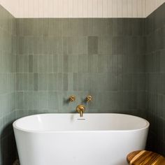 a white bath tub sitting next to a wooden stool