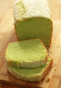 a loaf of green cake sitting on top of a wooden cutting board