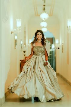 a woman in a long dress walking down a hallway