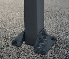 there is a small black object on the ground next to a pole with two legs