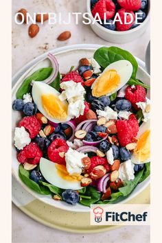 a salad with spinach, blueberries, raspberries and hard boiled eggs