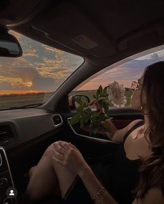 a woman sitting in the driver's seat of a car with flowers on the dashboard