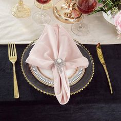 a place setting with pink napkins and goldware