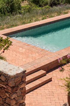 an empty swimming pool with steps leading up to it and flowers in the foreground