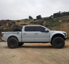 a white truck parked on top of a dirt road