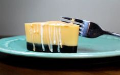 a piece of cheesecake on a plate with a fork stuck in the cake and drizzled with icing