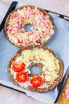 two bagels with cheese, tomatoes and ham on them