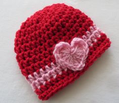 a red and white crocheted hat with a pink heart on it's side