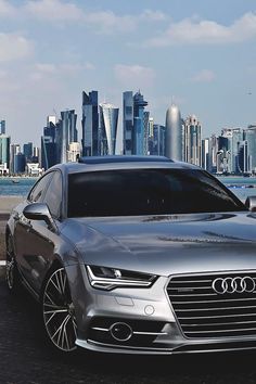 a silver car parked in front of a city skyline