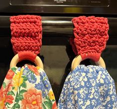 two crocheted cloths with wooden handles are hanging on the oven door handle