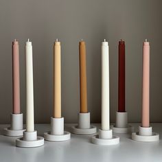 five different colored candles are lined up on pedestals