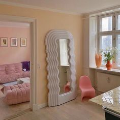 a living room filled with furniture and a large mirror on top of a wall next to a window