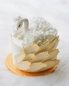 a cake with white flowers and a swan on it's top is sitting on a gold plate