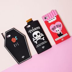 three different packagings on a pink and white surface with one has a skull, the other has an apple