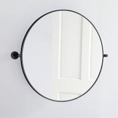 a round mirror hanging on the wall next to a white door with a black handle