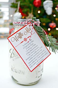 a mason jar filled with white and red christmas decorations sitting next to a christmas tree