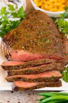 a large piece of steak on a plate with green beans and macaroni salad