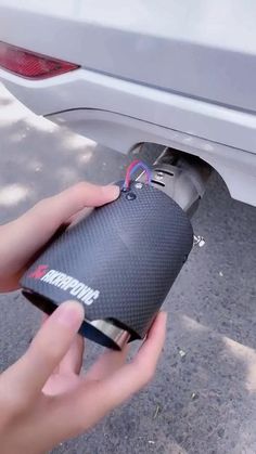 a person is holding an electronic device in front of a car's tailgate