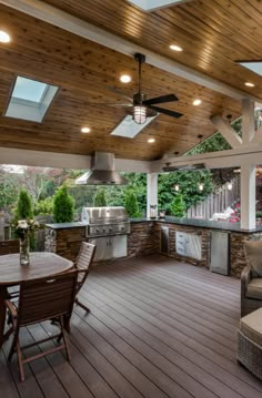 an outdoor kitchen and living room with wood flooring, ceiling fans, and grill area