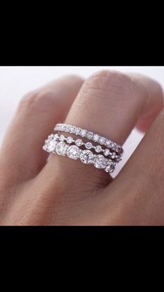 a woman's hand with three bands on it and two diamonds in the middle