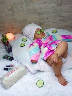 a baby is laying on a blanket with cucumbers around it