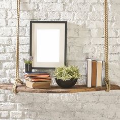 a white brick wall with a wooden shelf holding books and a framed photo on it