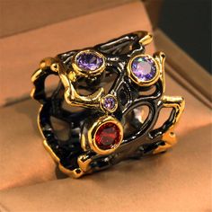 Purple and red crystals shine and 18-karat gold plating stands out against dark metal on this unique ring. 0.83'' W Silvertone copper / 18k gold-plated copper /?crystal Street Festival, Hollow Ring, Copper Crystal, Black Engagement Ring, Dark Metal, Zircon Jewelry, Festival Jewelry, Estilo Punk, Zircon Ring