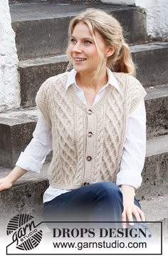 a woman sitting on some steps wearing a sweater