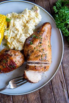 a white plate topped with meat, mashed potatoes and corn