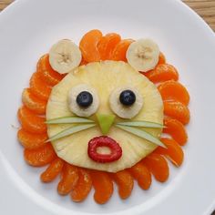 a white plate topped with sliced fruit and a face made to look like a lion