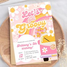 a pink and yellow camper birthday party card on a wooden platter with flowers