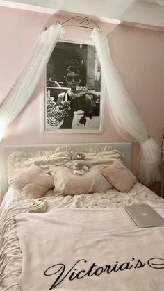 a bed with a white canopy over it and a poster on the wall above it that says victoria's