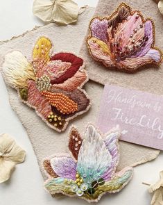 three embroidered flowers are sitting on a piece of fabric