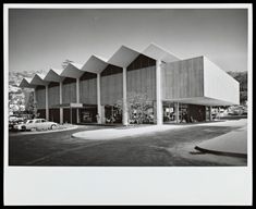 a black and white photo of a building with cars parked in front of the building